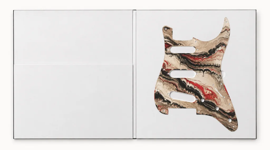 The SURGE pickguard, marbled cream, black and red, lying in its open box.