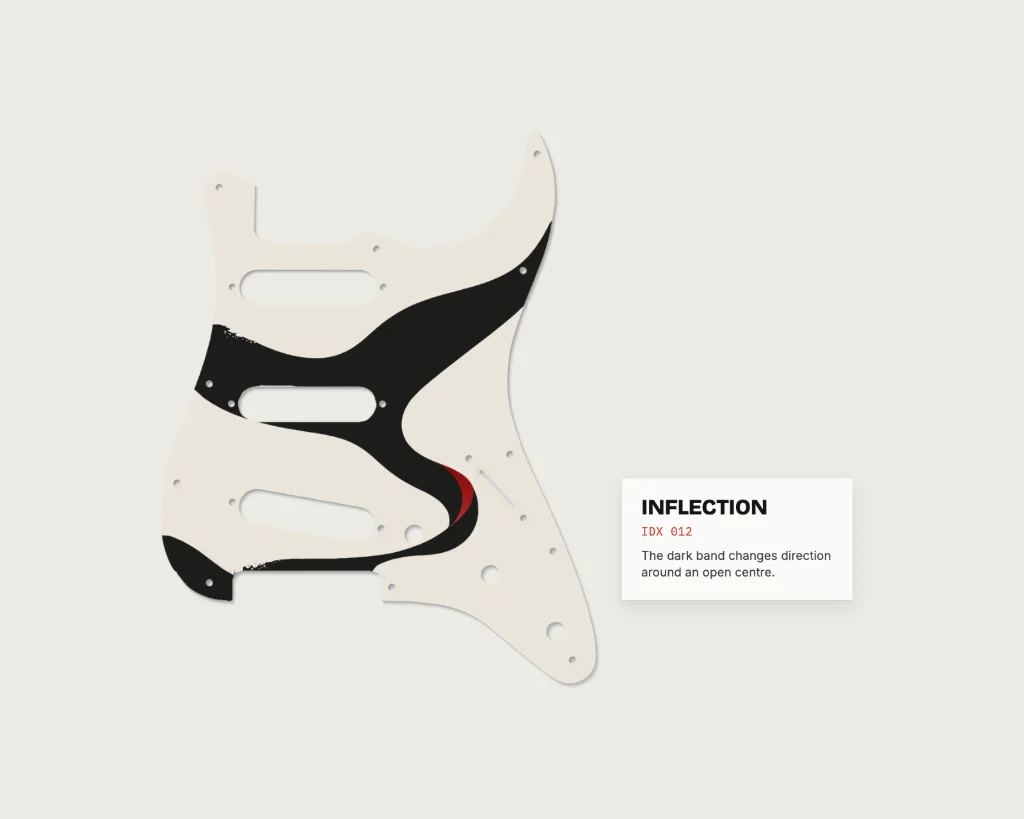 The INFLECTION pickguard hung like a museum piece, with its label: IDX 012, “The dark band changes direction around an open centre.”